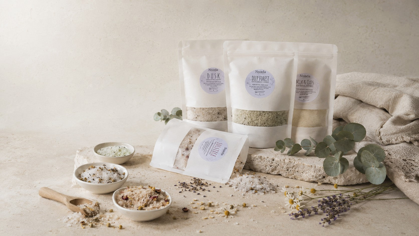 Nuada Naturals natural bath soak pouches arranged with dishes and botanicals