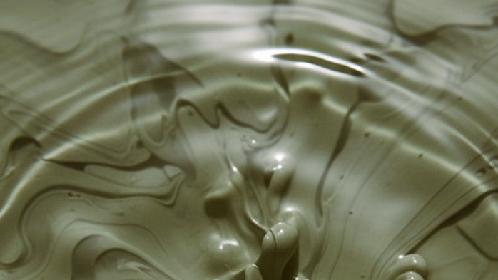 Close-up of green clay mixing with water.