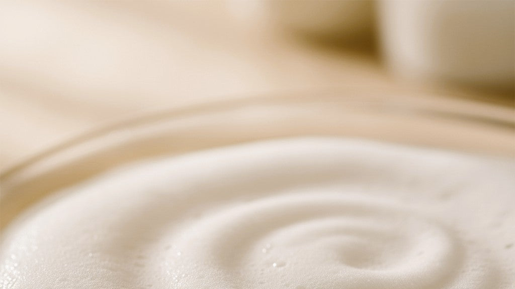 Close-up of a swirling pattern of white lather on a wooden surface.