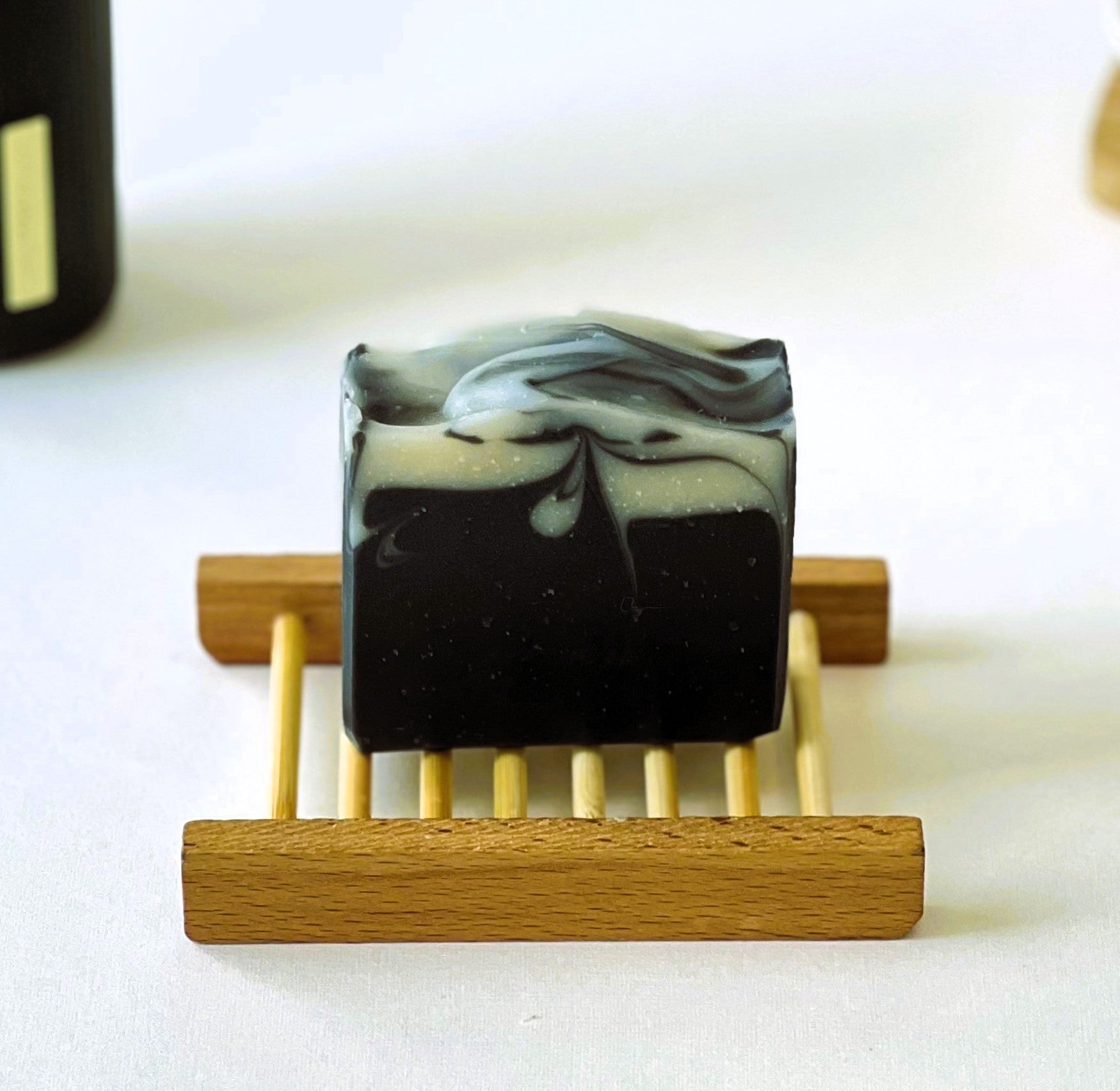 Nuada Naturals Benedictus charcoal soap bar with white marble swirl on wooden tray