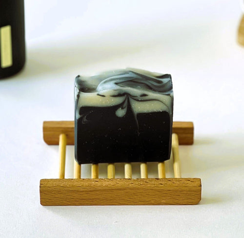 Nuada Naturals Benedictus charcoal soap bar with white marble swirl on wooden tray