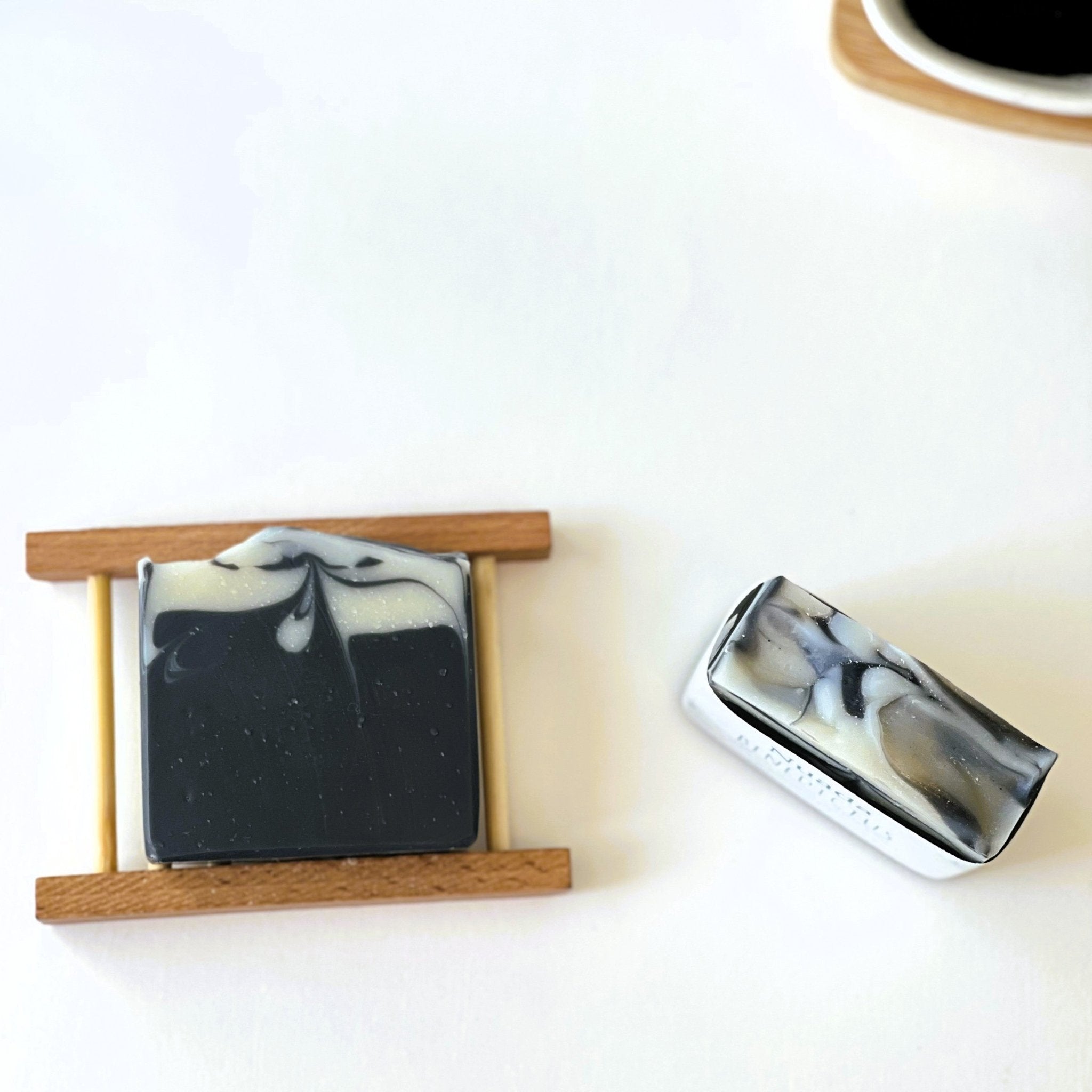 Top-down view of Nuada Naturals Benedictus charcoal soap bars on white background