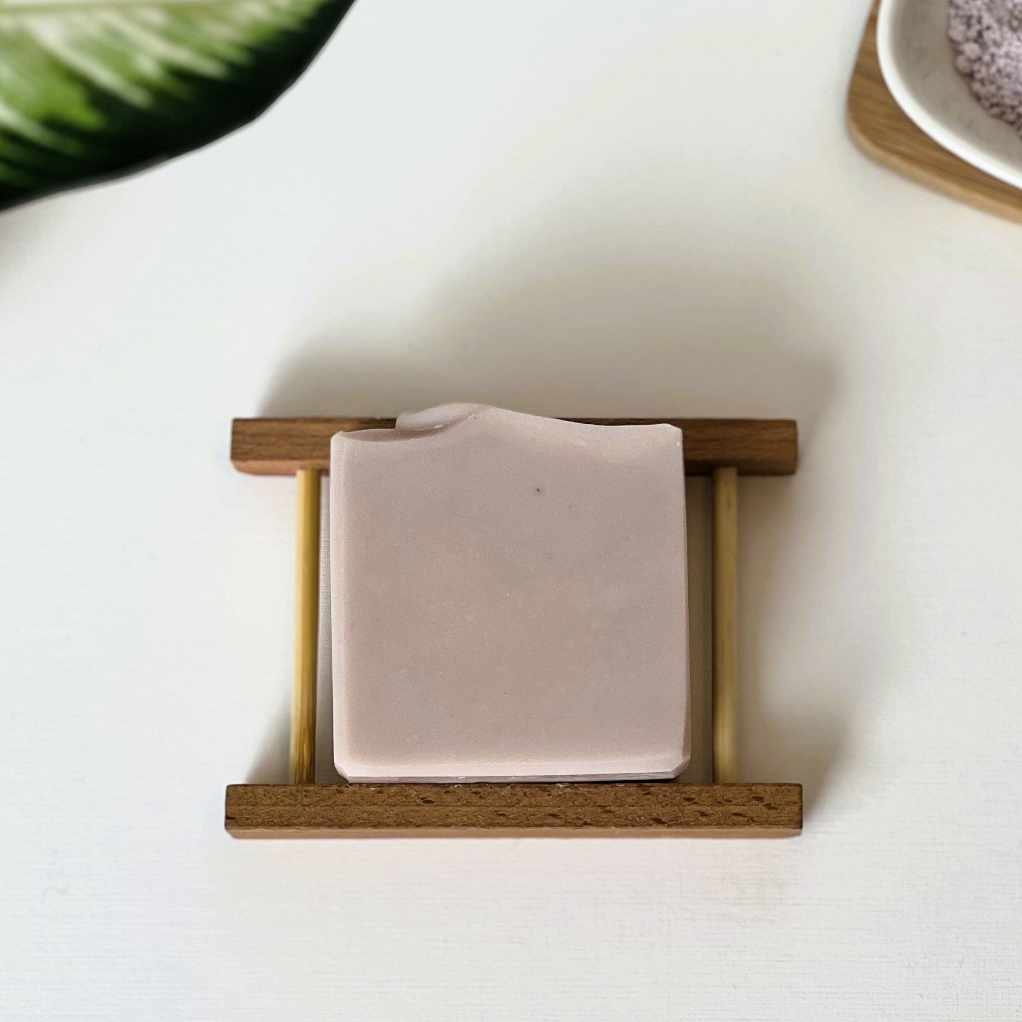 Top-down view of Nuada Naturals Dusk lavender soap bar on a wooden tray