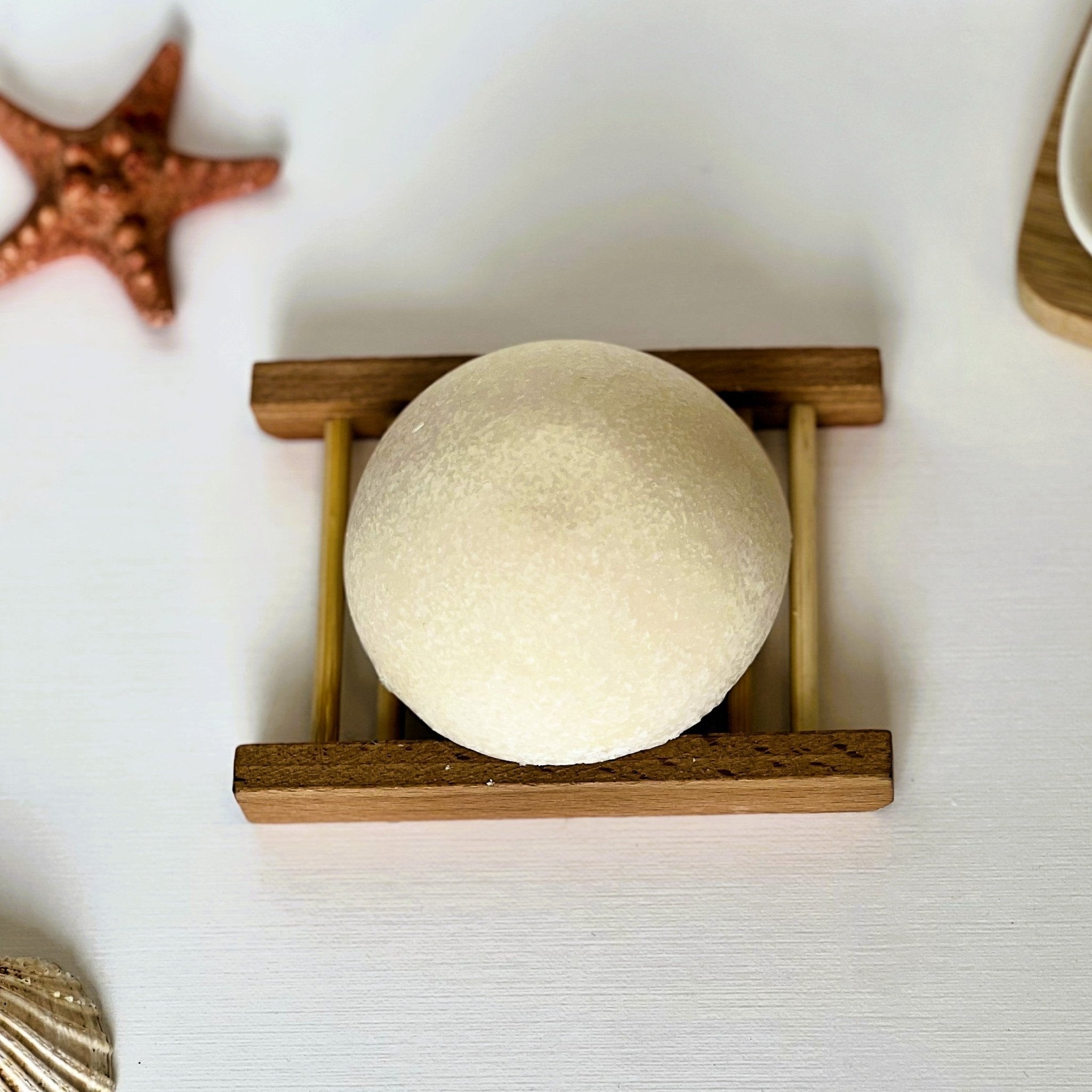 Top-down view of Nuada Naturals Golden Shore round sea salt soap on wooden tray