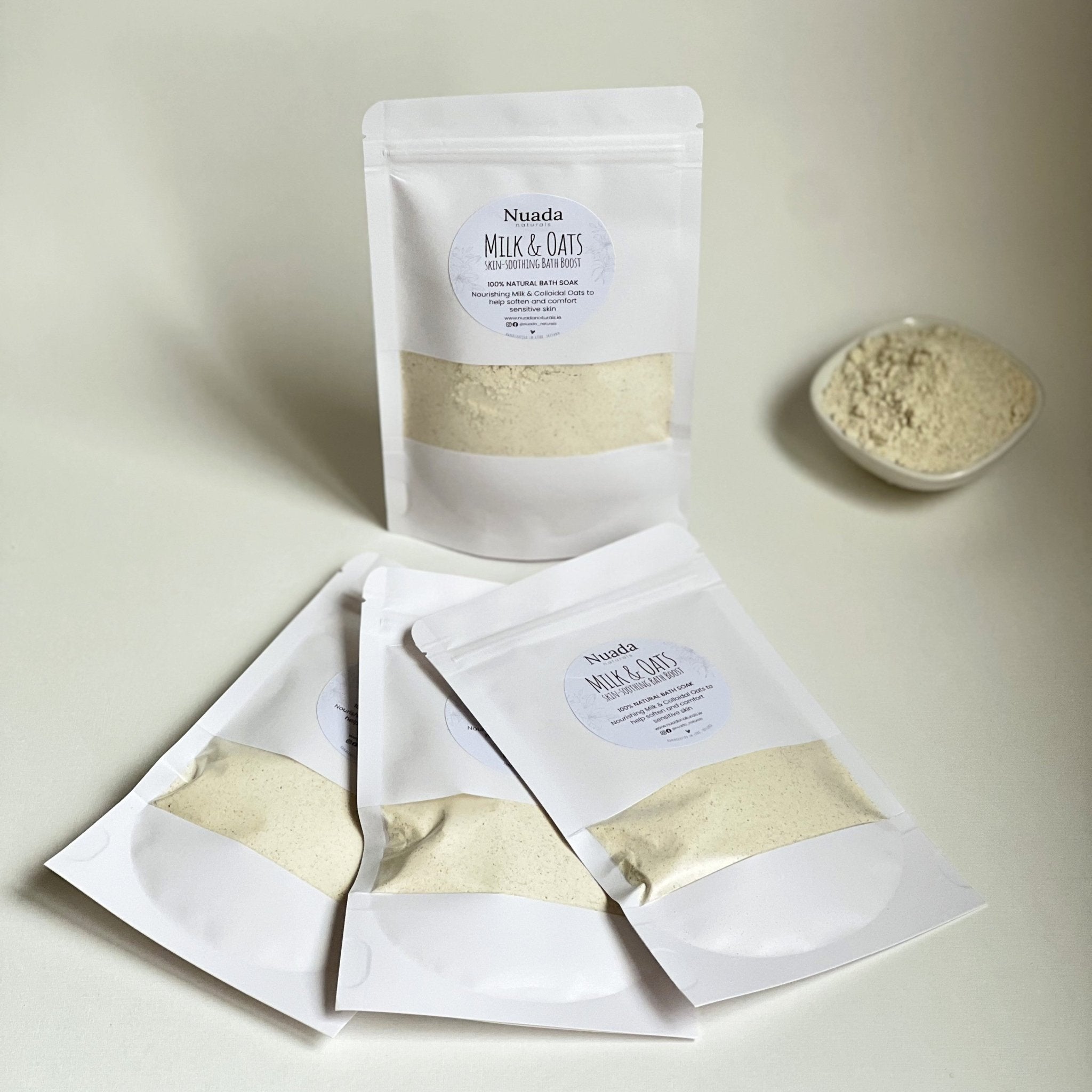 Multiple Nuada Naturals Milk and Oats bath boost pouches with powder in bowl