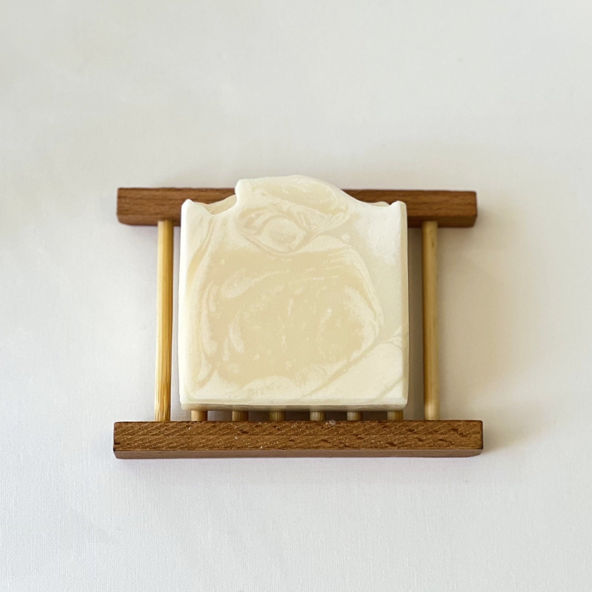 Top-down view of Nuada Naturals Solstice yellow clay soap bar on a wooden dish